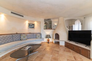 Una sala de estar con sofá, televisión y chimenea.
