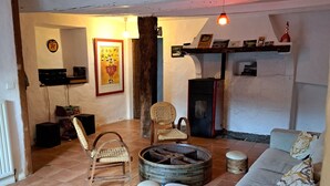 A living room with a sofa, two wicker chairs, a wooden coffee table, a fireplace, and a wall-mounted shelf with pictures. - Authentic 13th-century Cévennes house (Thoiras-Corbès)