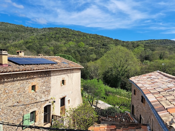 A stone building with a tiled roof, a small window, and a staircase leading to a door. - Authentic 13th-century Cévennes house (Thoiras-Corbès)