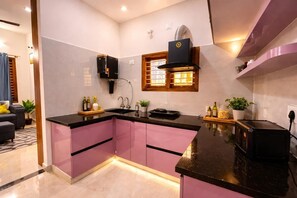 A modern kitchen with pink cabinets, a black countertop, and a built-in oven.
