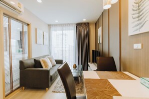 Ein modernes Hotelzimmer mit Sofa, Esstisch und Vorhängen.