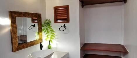 A modern bathroom with a white sink, mirror, and wooden shelves.