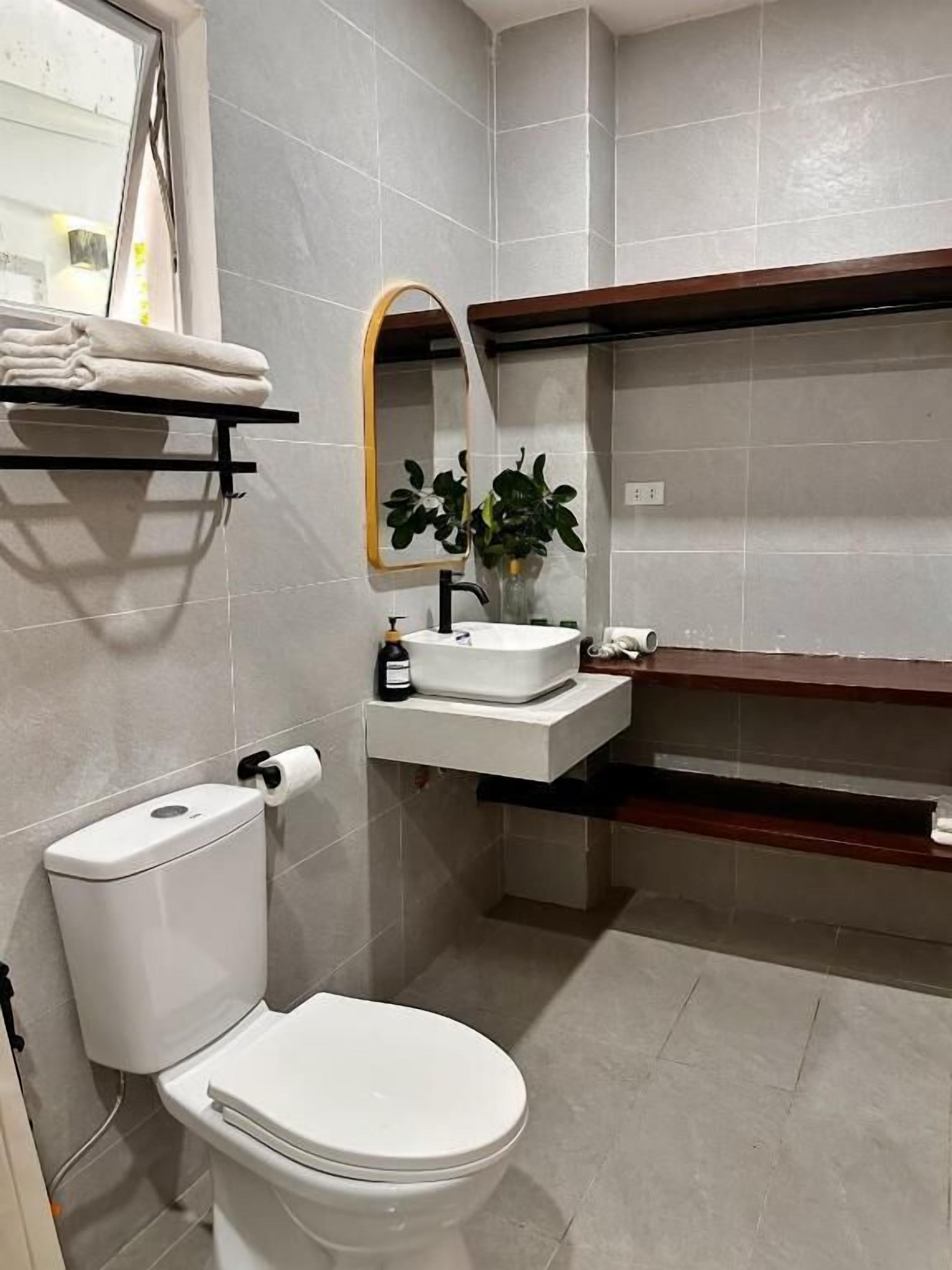 A bathroom with a toilet, sink, mirror, and towel rack.