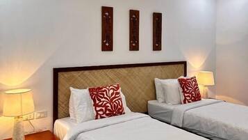 A hotel room with two beds, a wooden headboard, bedside lamps, and a ceiling fan.