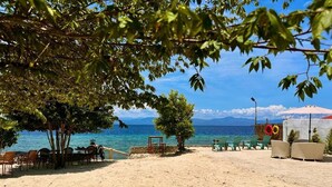 Una playa con asientos al aire libre, una mesa y sillas.