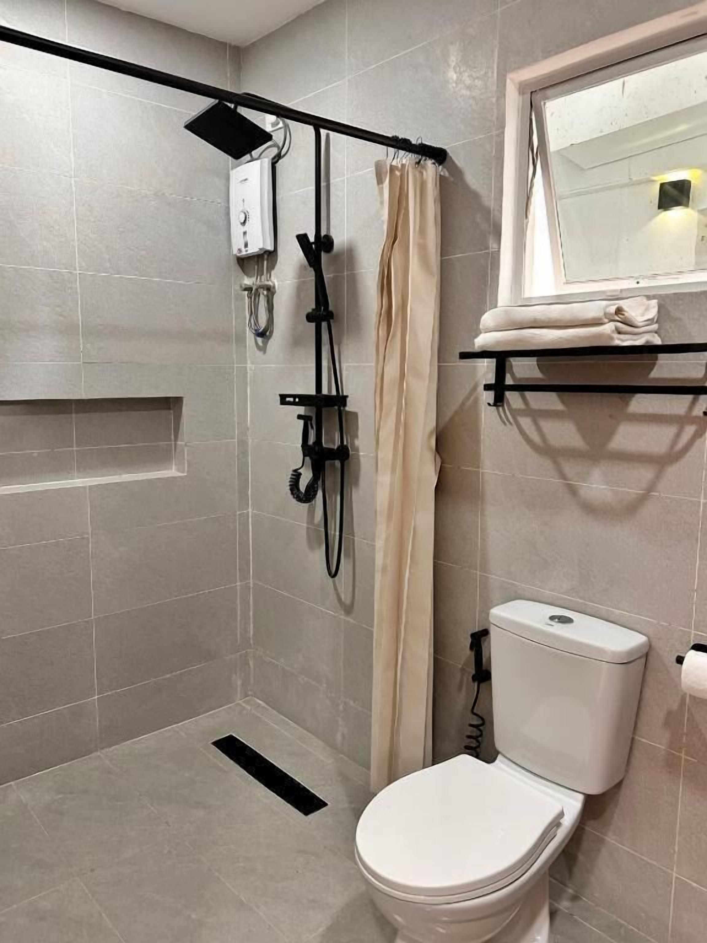 Baño con ducha, inodoro y ventana.