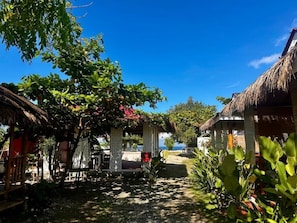 A pathway leading to a beach with thatched-roof structures and lush greenery.