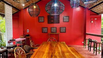 Un comedor con una mesa de madera, sillas de mimbre y lámparas colgantes de mimbre.