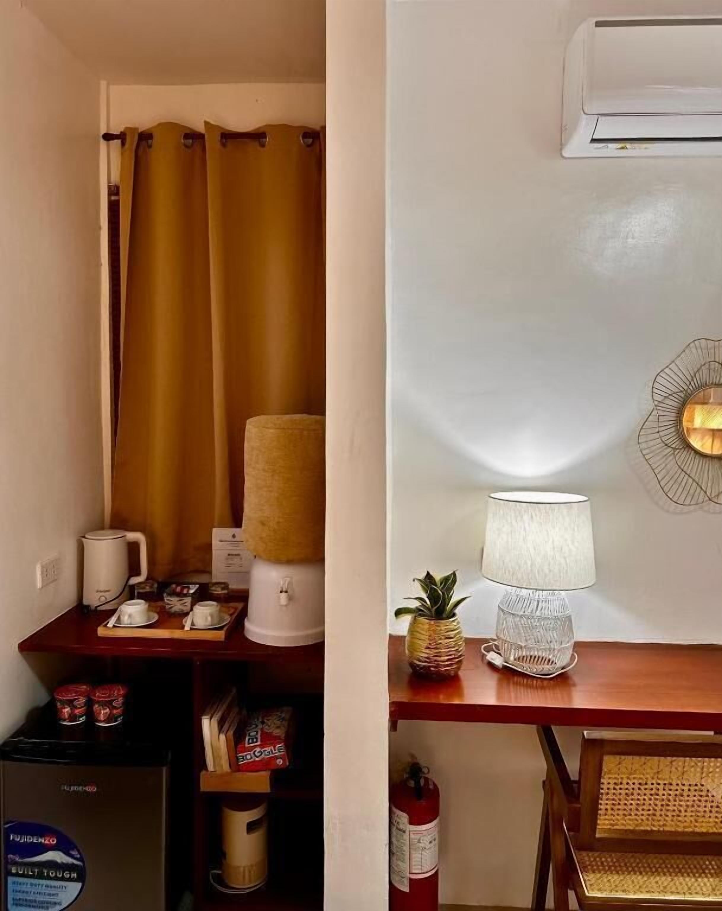 A small kitchenette with a coffee maker, a lamp, and a fire extinguisher.