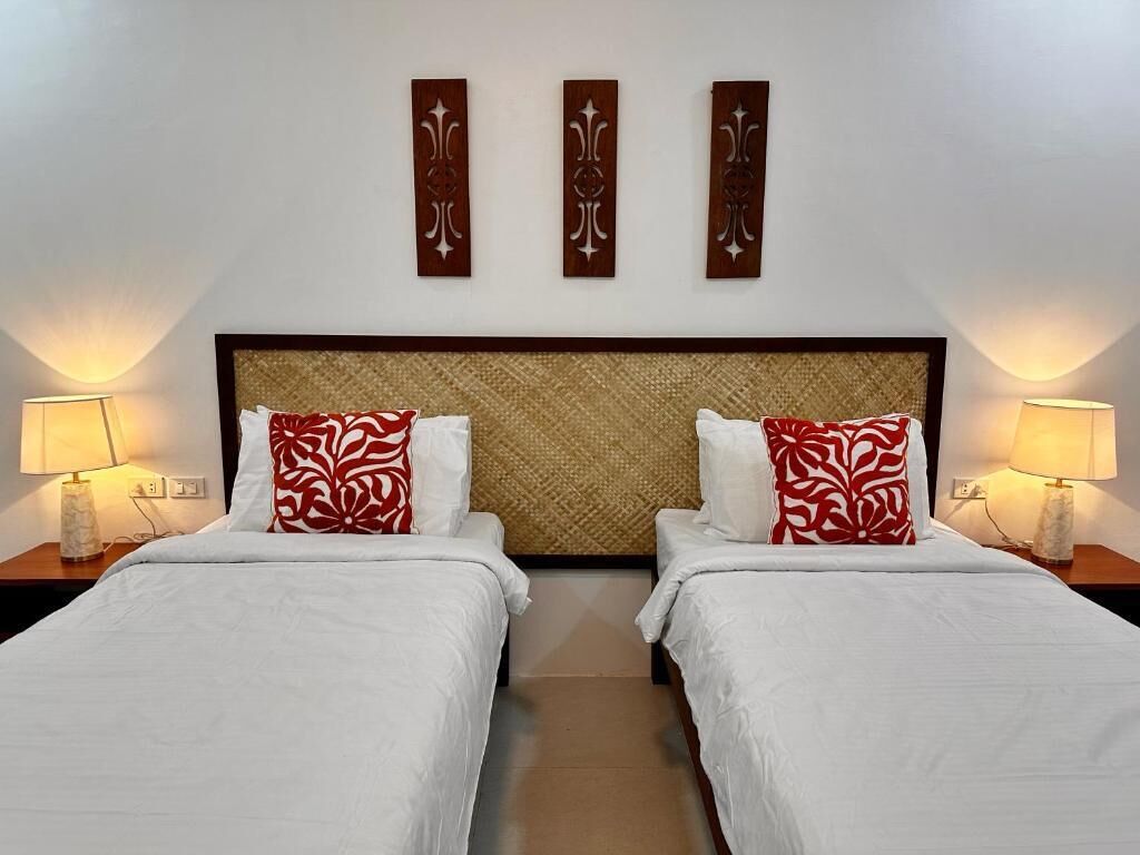A hotel room with two beds, a woven headboard, and wall-mounted decorative panels.