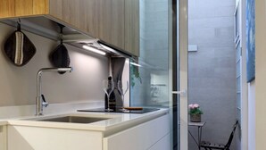 Een moderne keuken met een wit aanrecht, een roestvrijstalen spoelbak en verlichting boven het werkblad.