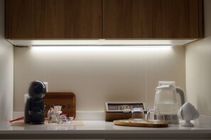 A kitchen counter with a coffee maker, a kettle, a tea sign, and a wooden cutting board. - Hostmate - Bari - Putignani (Bari)