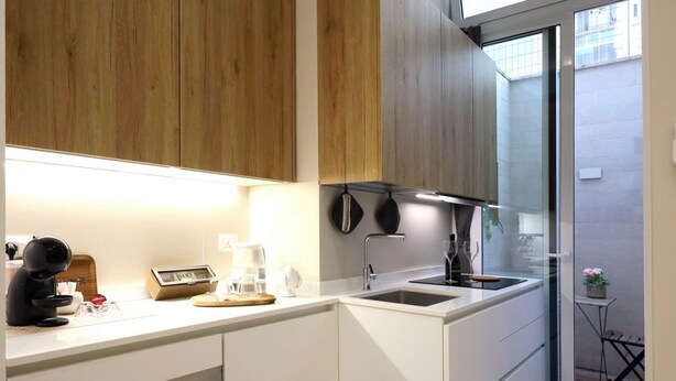 Een compacte keuken met een ingebouwde oven, een koffiezetapparaat en een spoelbak.