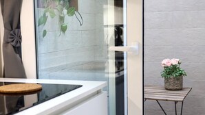 Een moderne keuken met een glazen deur, een tafeltje met een plant en een bank.