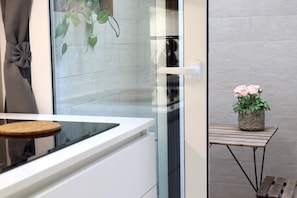 A modern kitchen with a glass door, a small table with a plant, and a bench. - Hostmate - Bari - Putignani (Bari)