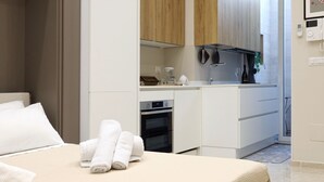 Een moderne hotelkamer met een bed, een kleine keukenhoek en een badkamer.