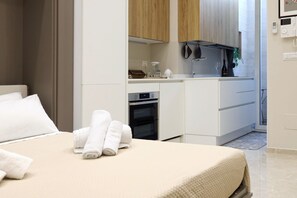 A modern hotel room with a bed, a small kitchenette, and a bathroom. - Hostmate - Bari - Putignani (Bari)