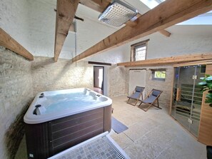 A spa area with a hot tub, two lounge chairs, and a glass door leading outside.