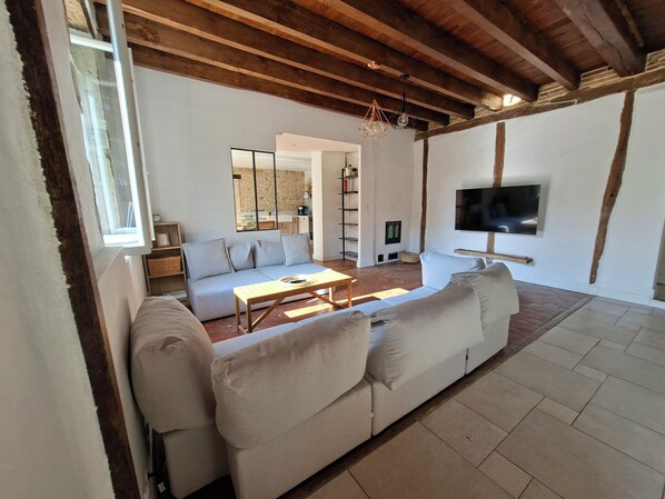 A living room with a sofa, coffee table, TV, and a stone wall.