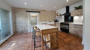 Een moderne keuken met een stenen muur, een houten eettafel en een groot fornuis.