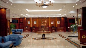 Un hall de hotel con una recepción, una araña de cristal y un sofá azul.