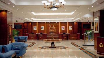 A hotel lobby with a reception desk, a chandelier, and a blue sofa.