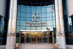 The entrance of the LUXE GRAND HOTEL with a glass facade and a prominent sign above the doors. - The Luxe Grand Hotel (Dubai)
