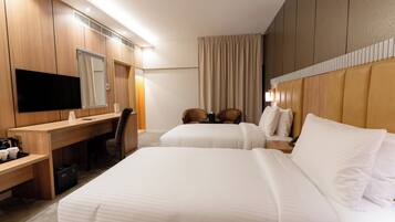 A hotel room with two beds, a desk, a chair, a television, and a large mirror.