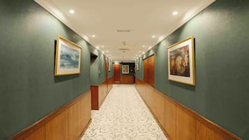 A hallway with green walls, wooden paneling, and patterned carpet.