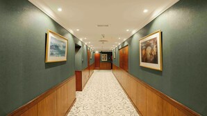 Un pasillo con paredes verdes, paneles de madera y alfombra estampada.