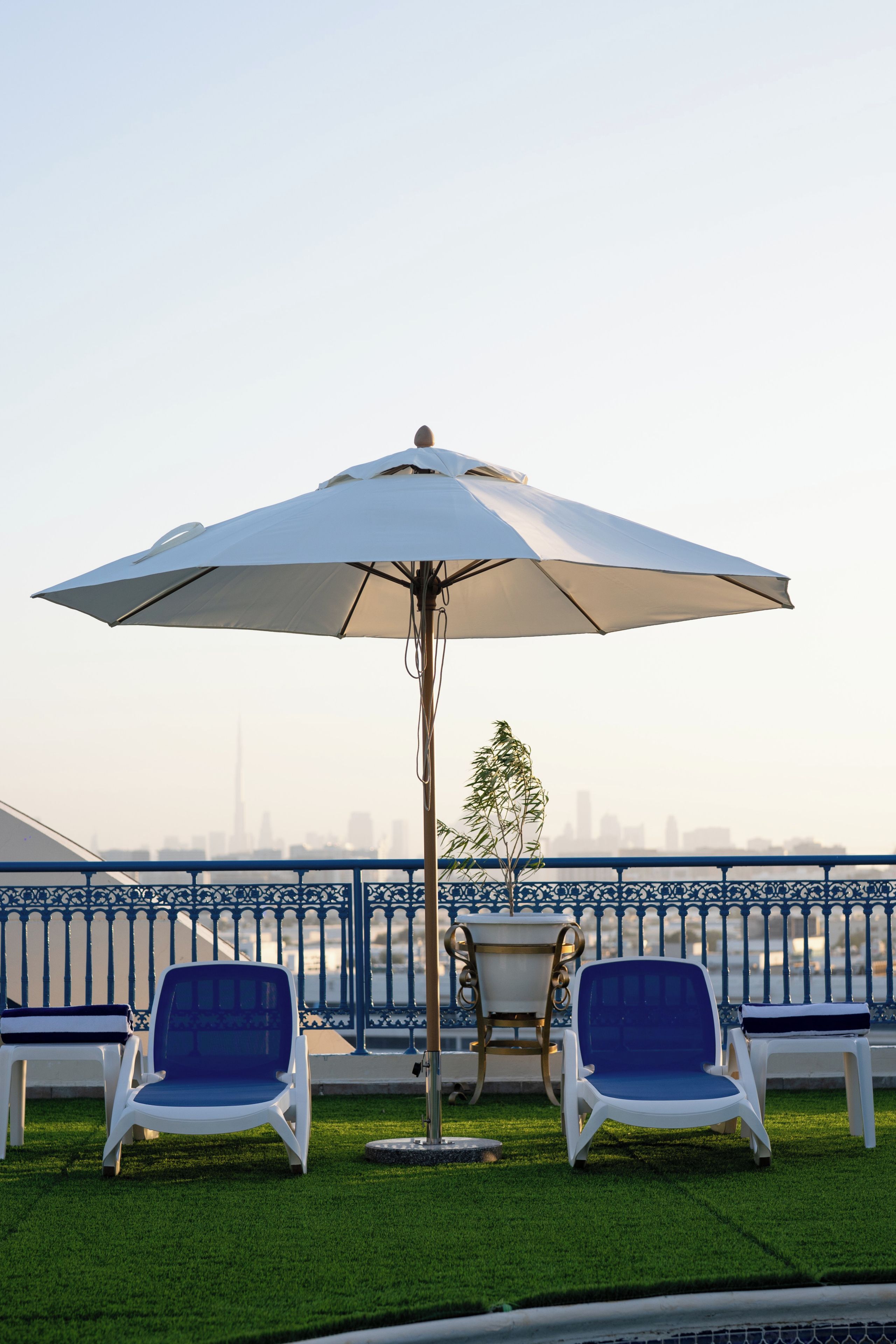 Une terrasse avec deux fauteuils, une table et un parasol.