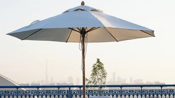 Une terrasse avec deux fauteuils, une table et un parasol.