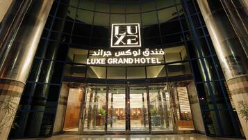 LUXE GRAND HOTEL -hotellin sisäänkäynti, jossa on lasijulkisivu ja suuri, huomiota herättävä kyltti.
