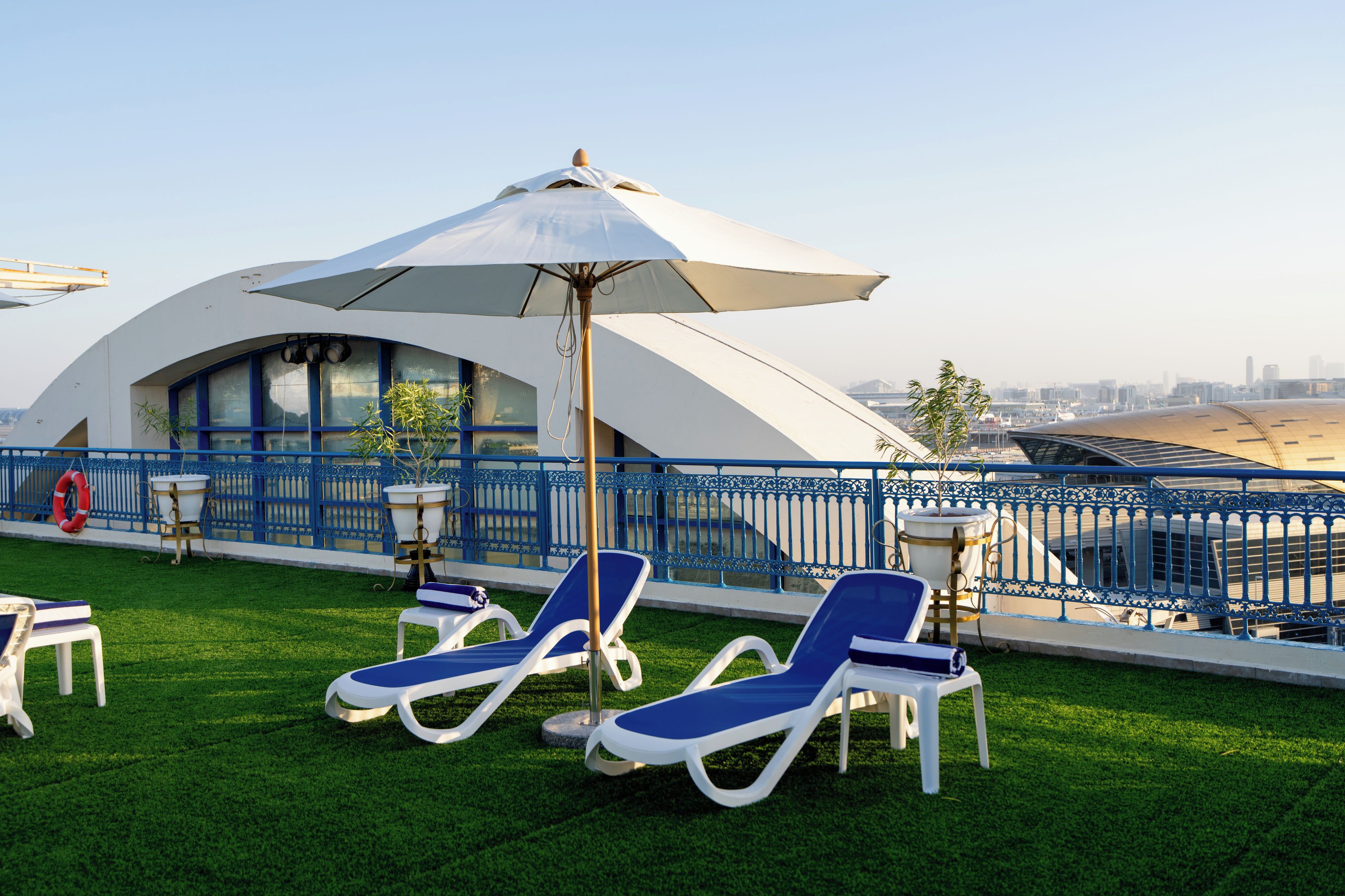 En tagterrasse med liggestole og en stor parasol med udsigt over bybilledet.