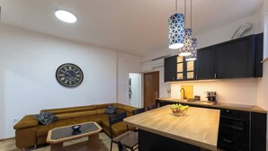 Une cuisine moderne avec un îlot central en bois, des meubles de couleur noire et une horloge au mur.