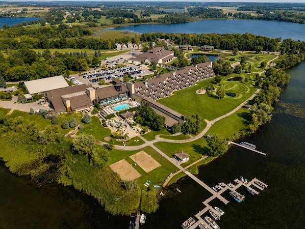 An aerial view of a resort with a swimming pool, golf course, and docked boats.