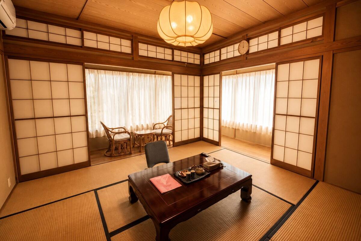 Una habitación japonesa tradicional con suelo de tatami, una mesa de madera y un muro con puertas correderas shoji.