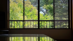 Una habitación con un ventanal grande, suelo reflectante y vistas a abundante vegetación.