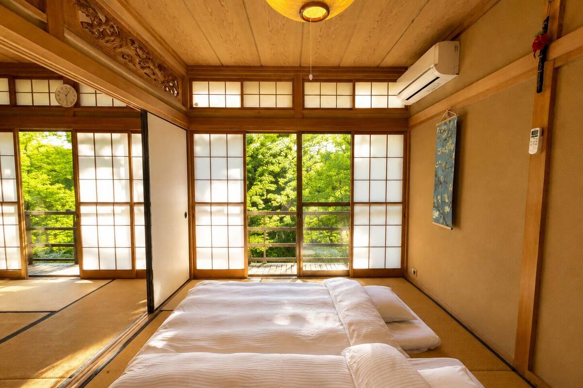 Una habitación japonesa tradicional con suelo de tatami, puertas correderas y una cama con ropa blanca.