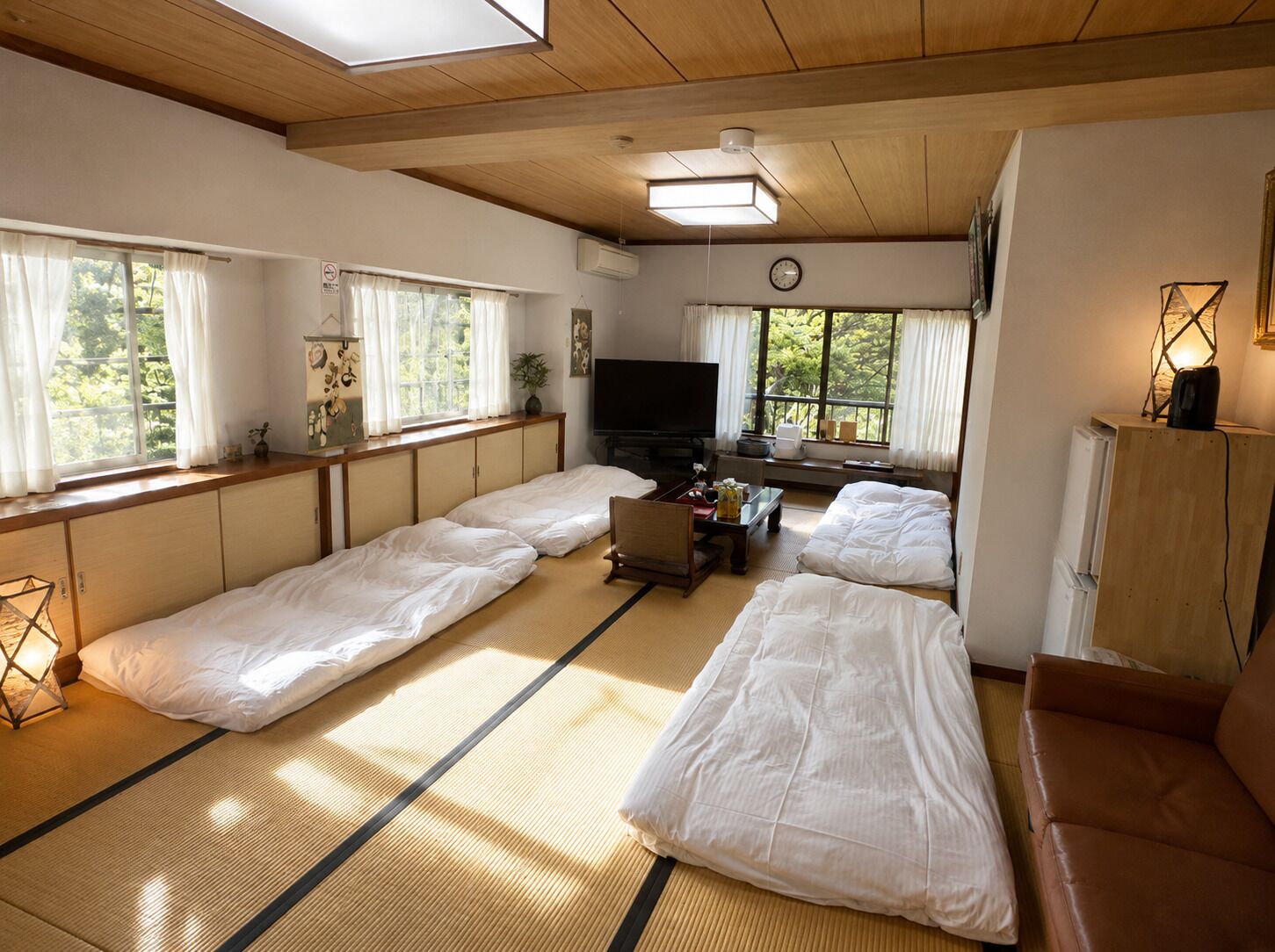 A traditional Japanese-style room with tatami flooring, a television, and a sofa.