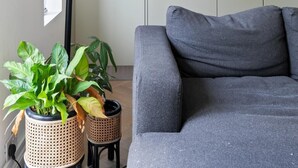A modern kitchen with white cabinets, a black curved light fixture, and a grey sofa. - Spacious flat in the heart of Tottenham (London)