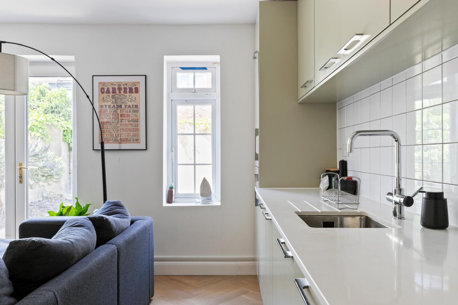 A modern kitchen with white cabinetry, a stainless steel sink, and a black coffee maker.