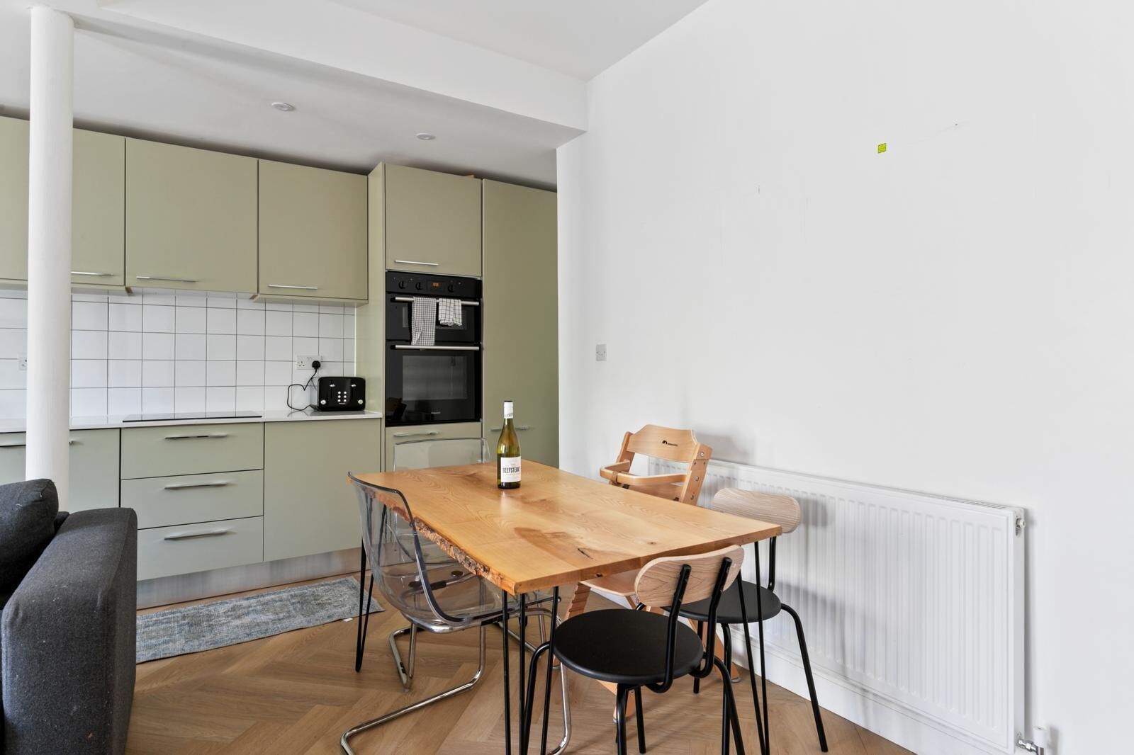 Een moderne keuken met een eettafel, stoelen en een fles wijn.
