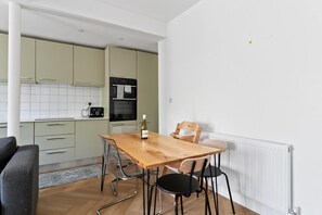 Una cucina moderna con un tavolo da pranzo, sedie e una bottiglia di vino.