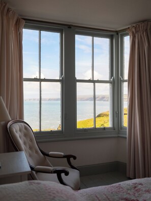 Ein Zimmer mit einem großen Erkerfenster, einem Sessel und einem Bett.
