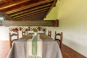 A dining table with a woven table runner, wooden chairs, and a wall-mounted plant arrangement. - Family Villa Uitzenea with Garden, Near San Sebastián and Pamplona (Gorriti)