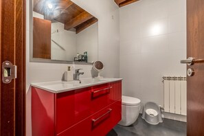 A bathroom with a white sink, red vanity, a mirror, a toilet, and a radiator. - Family Villa Uitzenea with Garden, Near San Sebastián and Pamplona (Gorriti)