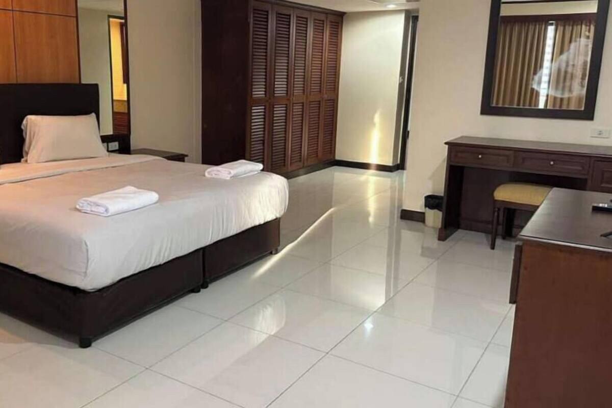 A hotel room with a bed, a desk, a chair, and a wardrobe.