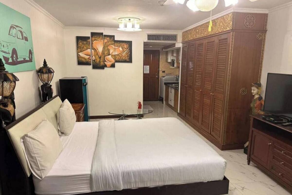 A bedroom with a bed, a desk, a wardrobe, and a television.