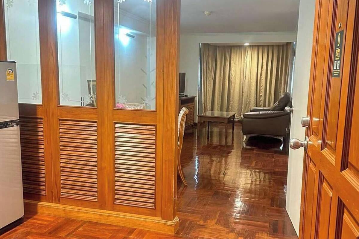 A room with a wooden floor, a sofa, a table, and a television.